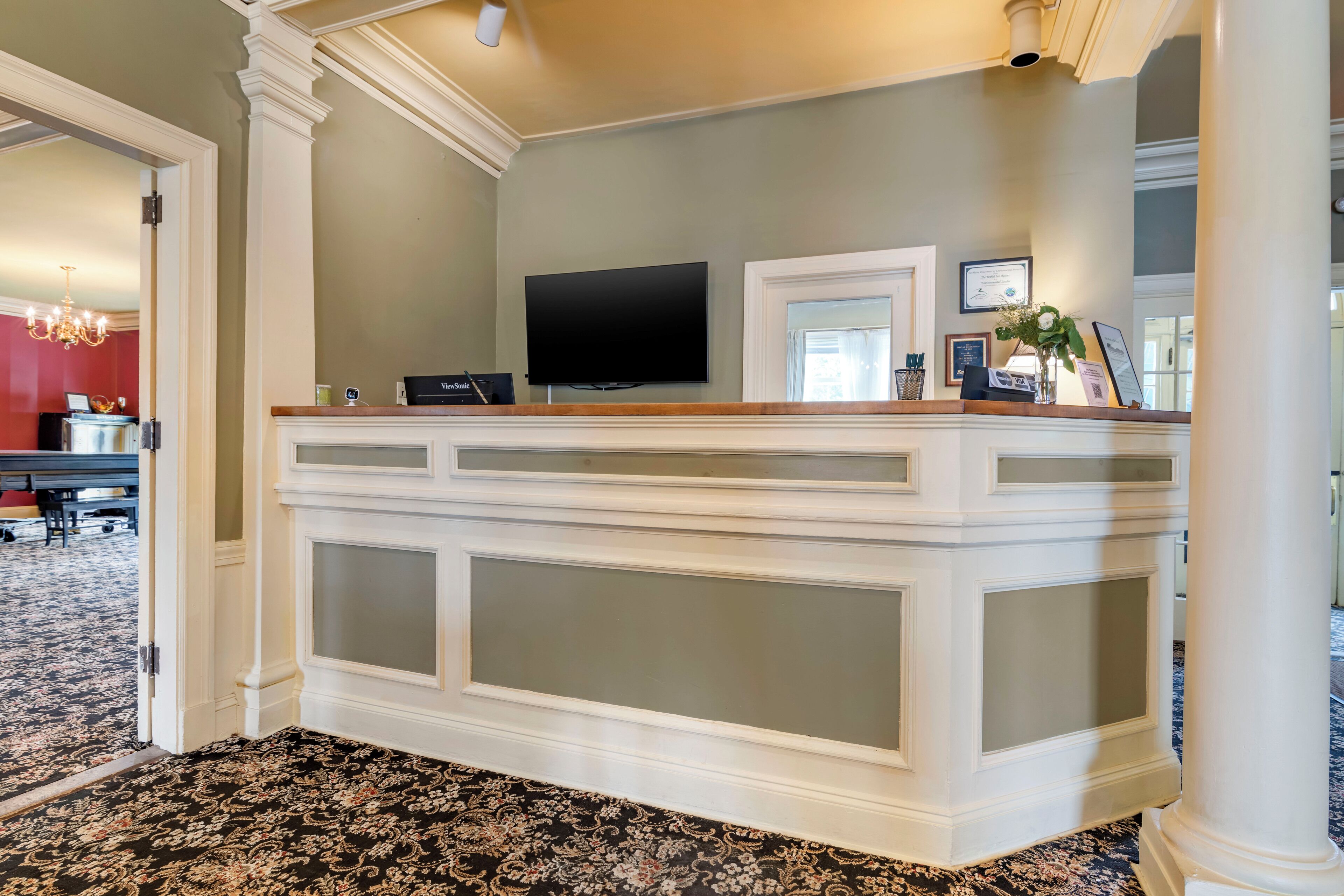 A reception area with a flat-screen TV, a reception desk, and framed certificates on the wall.
