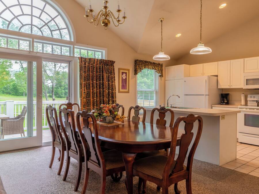A kitchen with a dining area, large windows, and a view of the outdoors.
