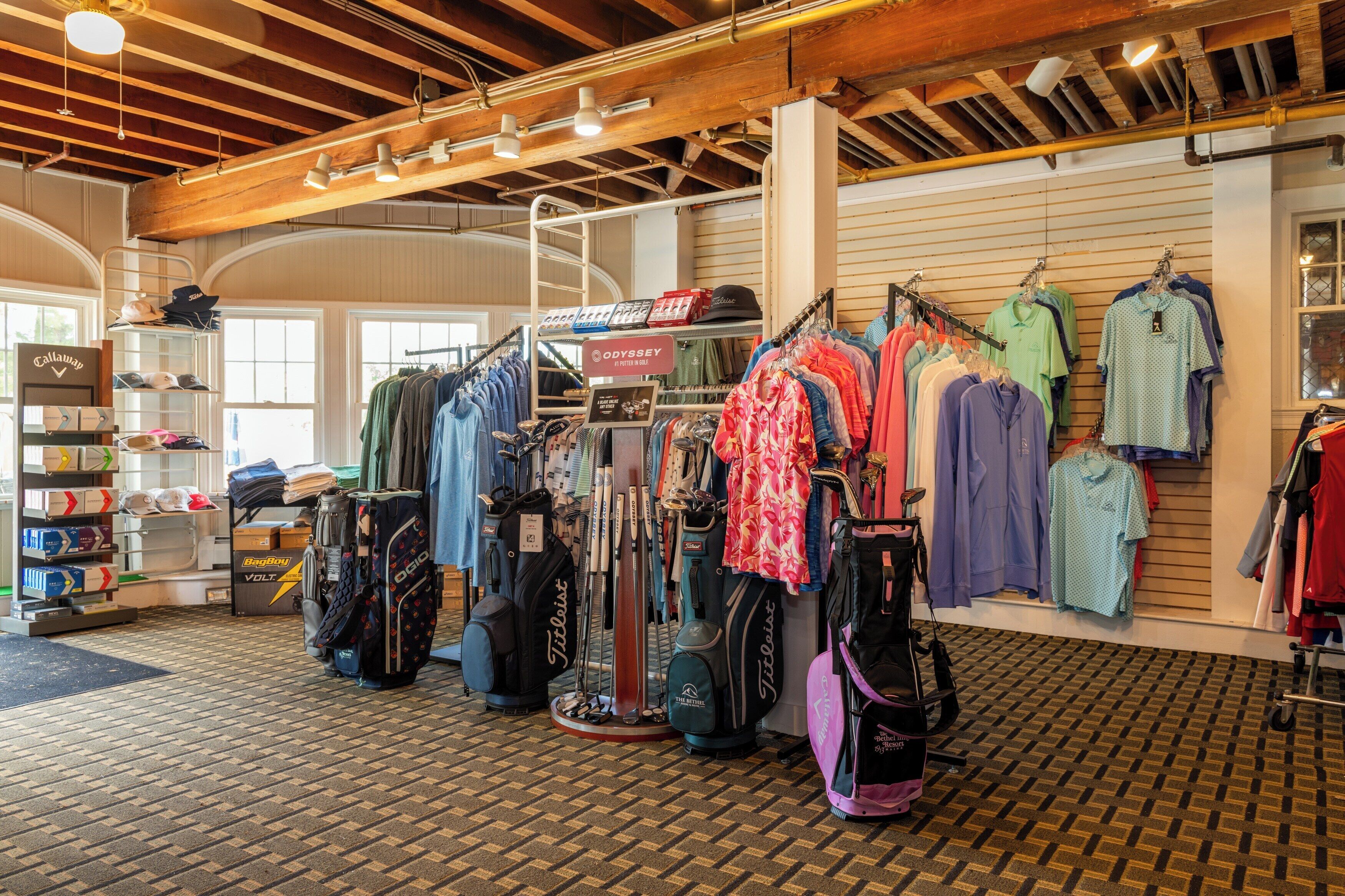 Un espacio comercial con estanterías llenas de bolsas de golf y ropa, vigas de madera en el techo y un piso con diseño.
