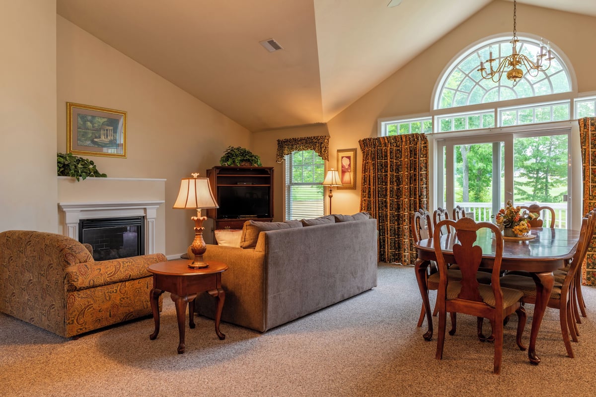 A living room with a fireplace, sofa, TV, and dining table with chairs.