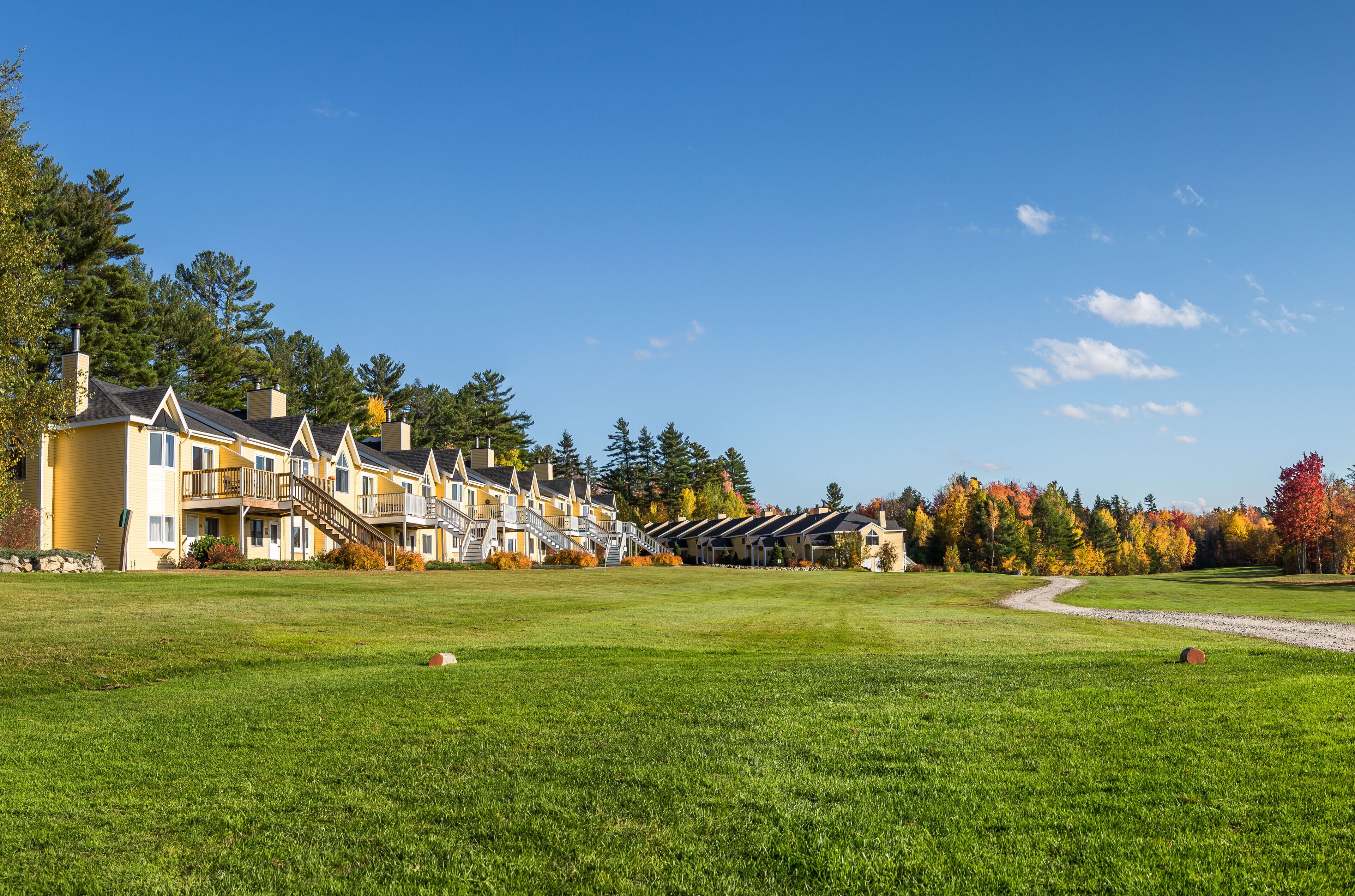 A row of yellow buildings with balconies and a grassy field in the foreground.
