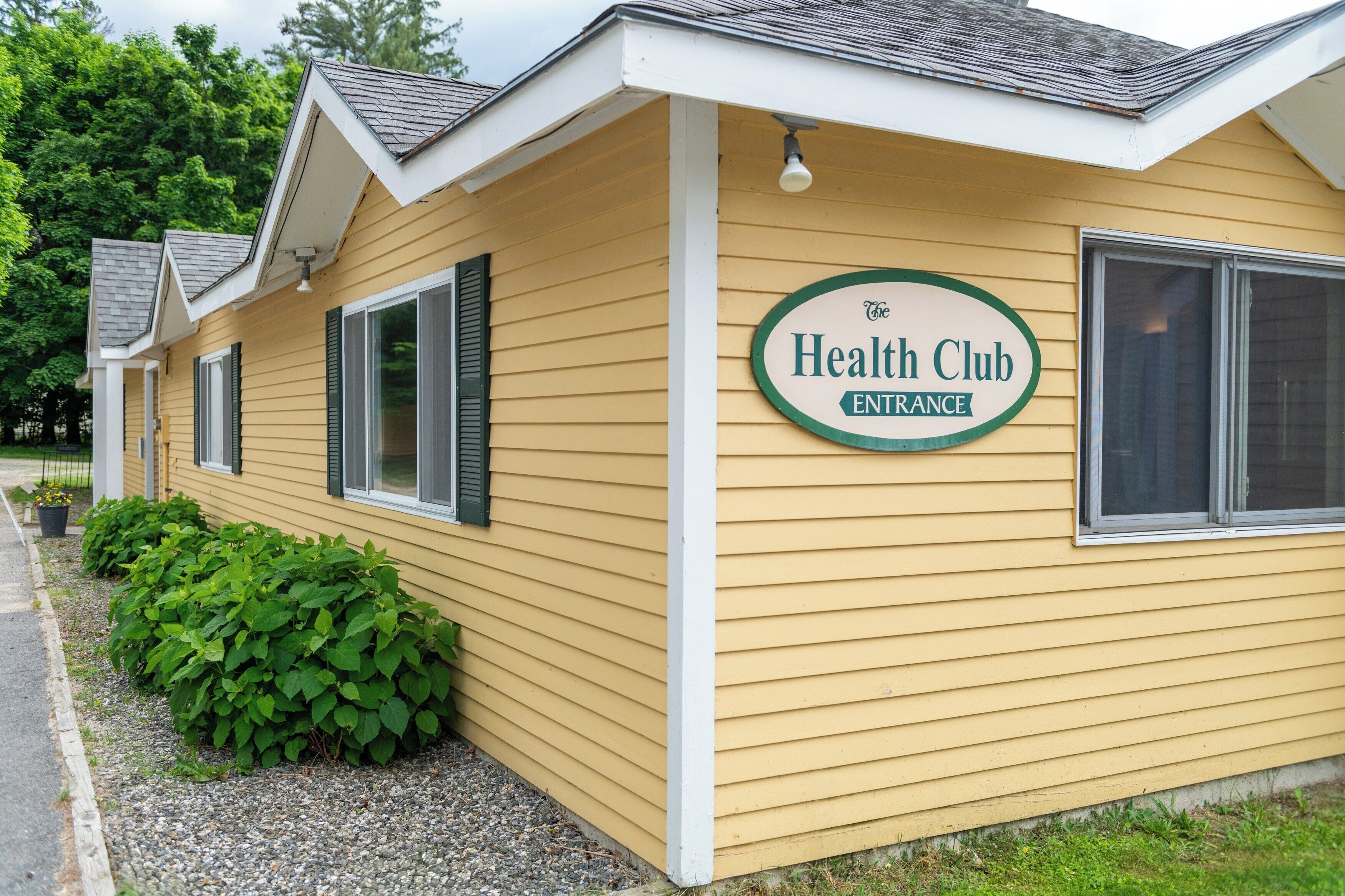 Un bâtiment jaune avec une enseigne indiquant « Entrée du club de santé ».