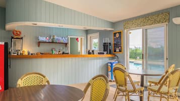 A bar area with a counter, seating, and a view of the outdoors.