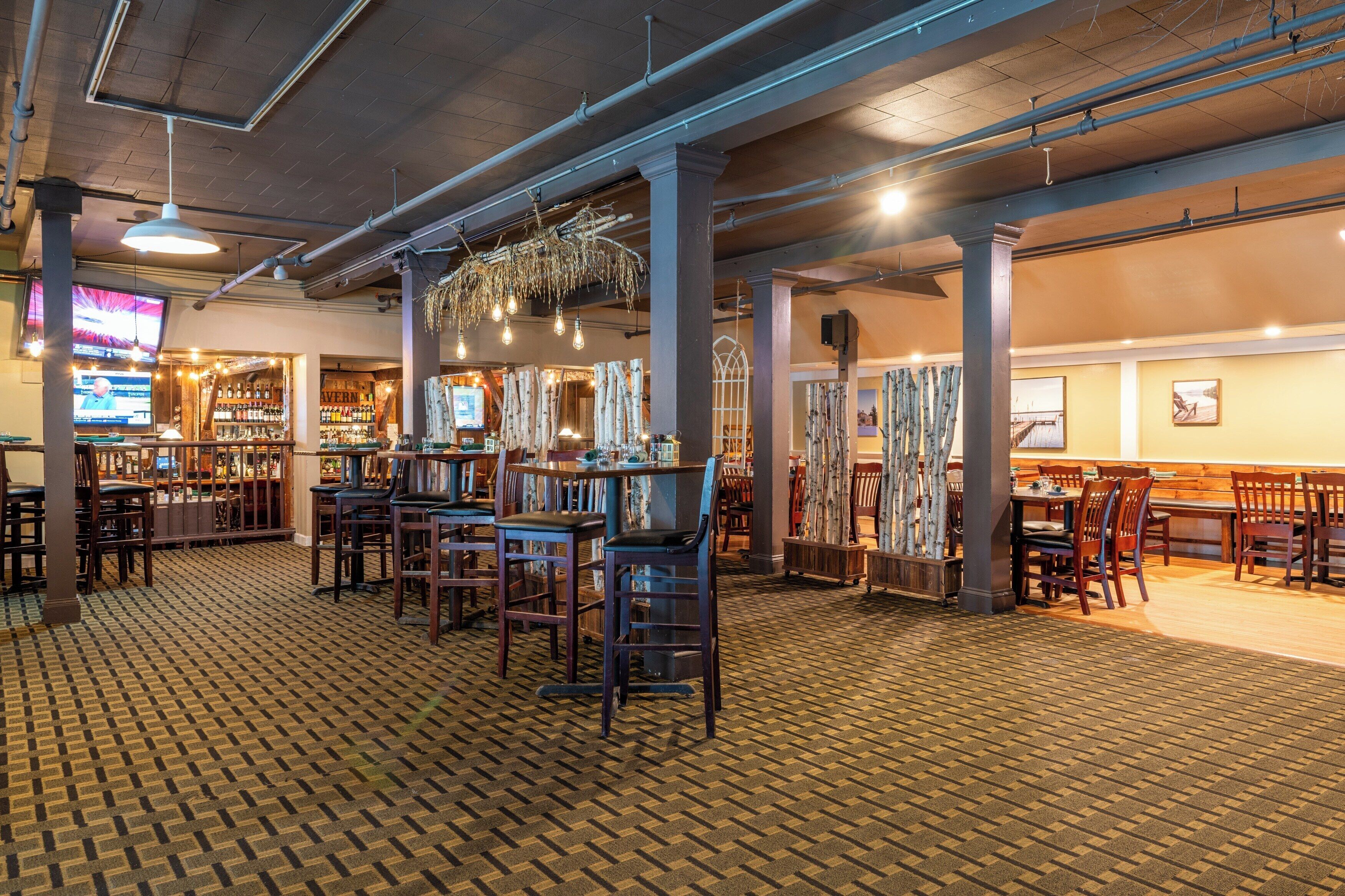 Un restaurant doté d’un sol en briques, de tables et de chaises en bois, de luminaires suspendus et d’un bar avec des étagères remplies de bouteilles.