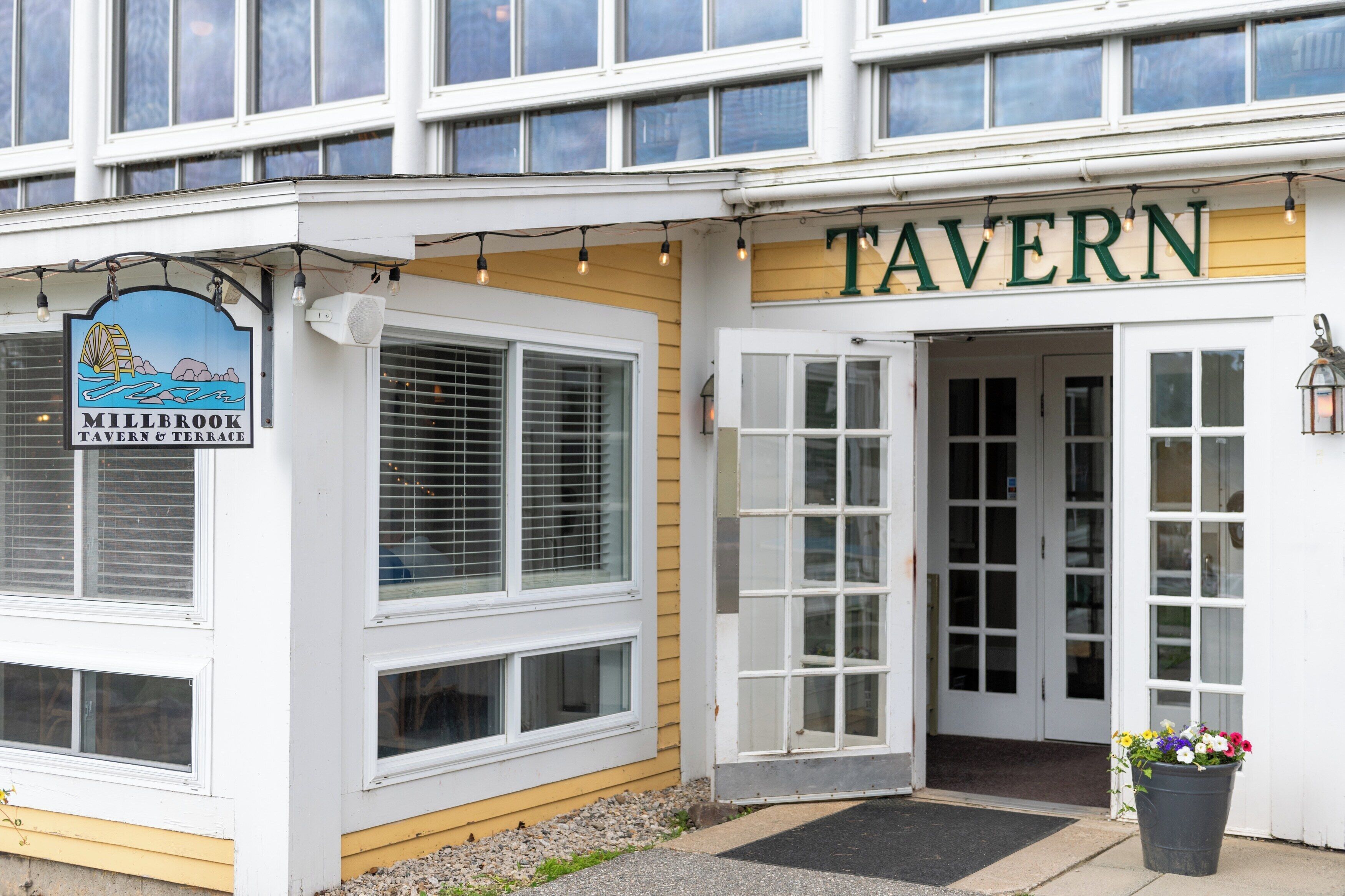 Eine Taverne mit einem Schild, auf dem 'TAVERN' steht, und einem kleineren Schild für 'Millbrook Tavern & Terrace'.