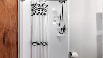 A bathroom with a shower curtain, a handheld showerhead, and a toilet paper holder.