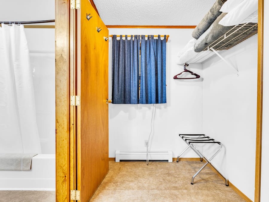 A bathroom with a shower curtain, a towel rack, a heater, and a drying rack.