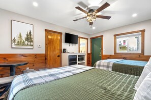 A hotel room with two beds, a ceiling fan, a TV, and a window with a view.