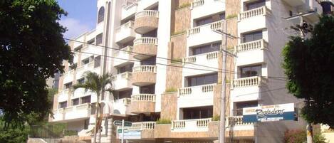 Un edificio de varios pisos con balcones, un cartel que dice 'El Fenon Del' y una calle delante.