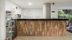 Un espace d’accueil comprenant un comptoir en bois, un bureau de réception et une vitrine en verre où sont exposés divers objets.
