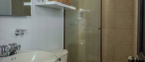 Un baño con inodoro, lavamanos y cabina de ducha de vidrio.