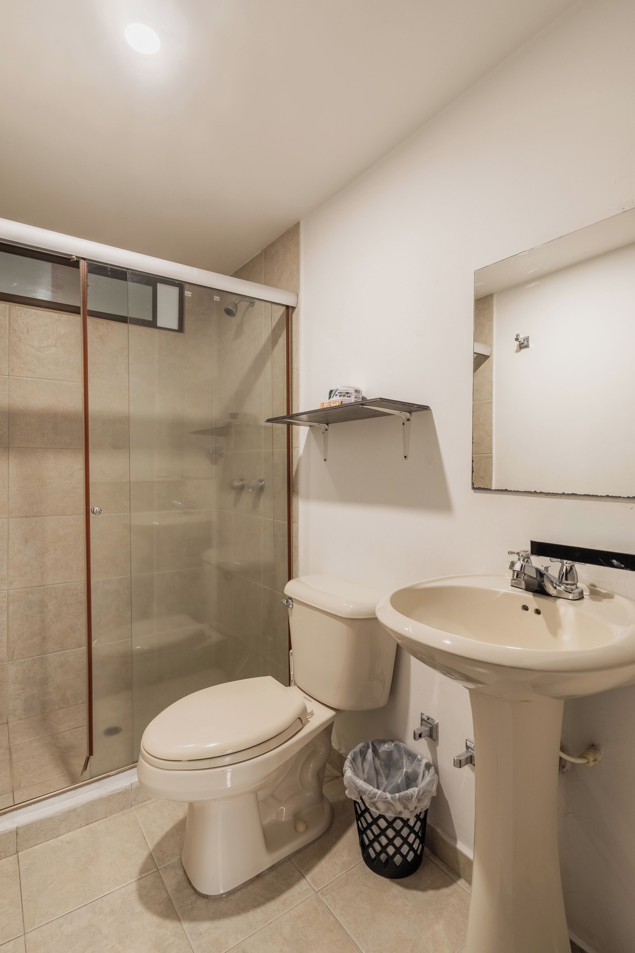 A bathroom with a toilet, sink, and glass-enclosed shower.