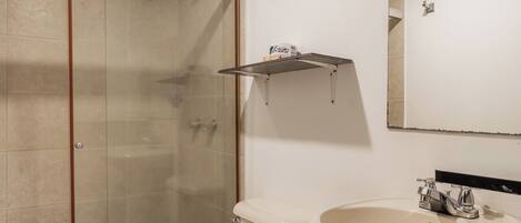 A bathroom with a toilet, sink, and glass-enclosed shower.