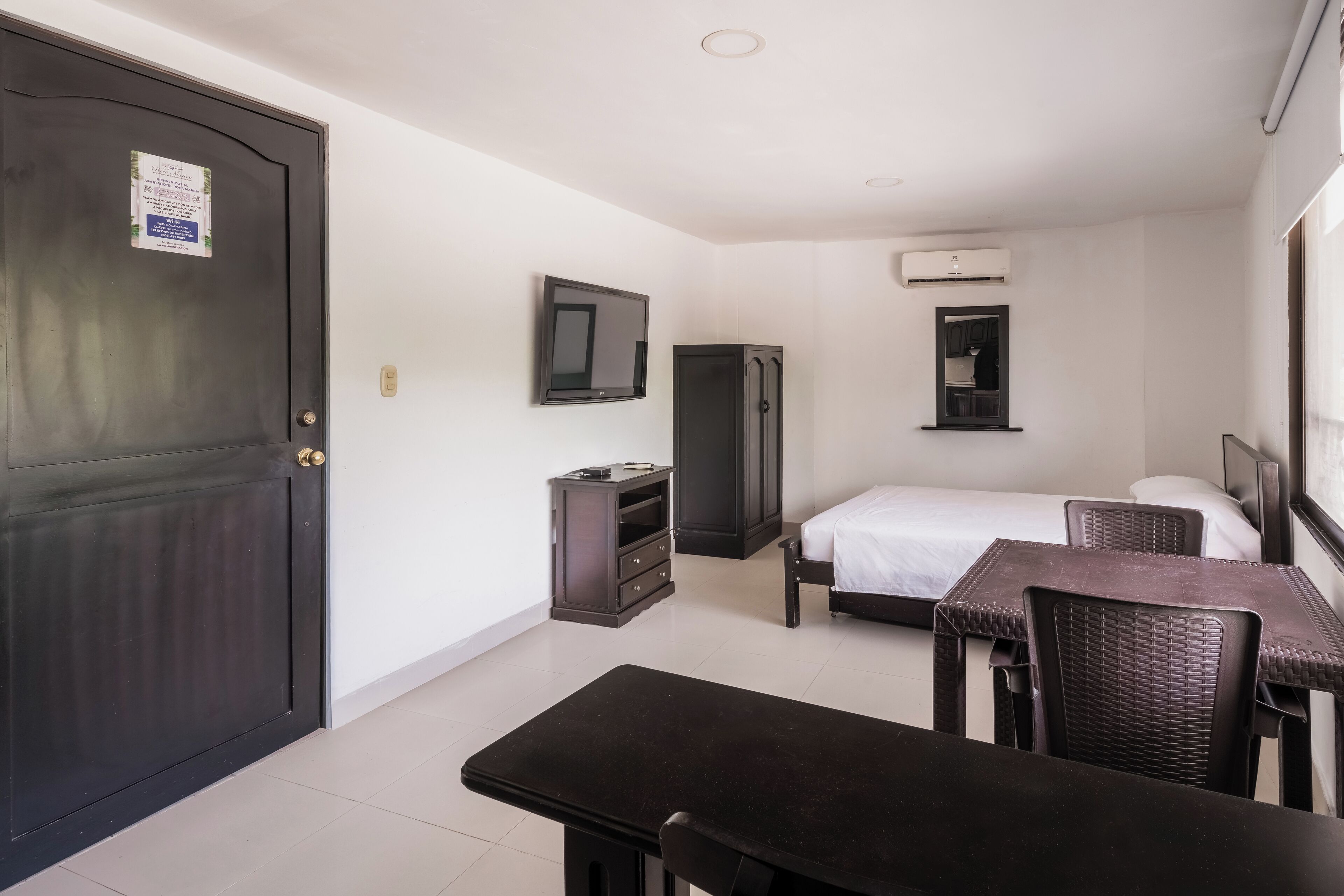 Ein Hotelzimmer mit Bett, Schreibtisch, Stuhl, Kleiderschrank und Fernseher.