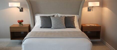 A modern bedroom with a large bed, two bedside tables, and wall-mounted lamps.
