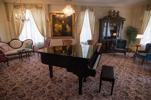 A grand room with a grand piano, plush seating, a chandelier, and a large painting. - Erik's Retreat in Minnesota (Edina)