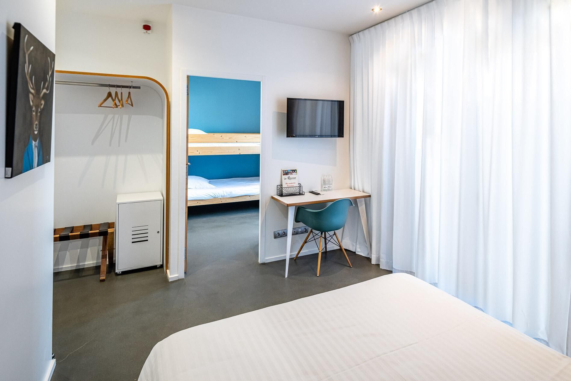 Une chambre d’hôtel comprenant un lit, un bureau avec une chaise, une télévision et une armoire.