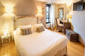 A bedroom with a large bed, a wooden headboard, a desk with a chair, and a window with curtains.