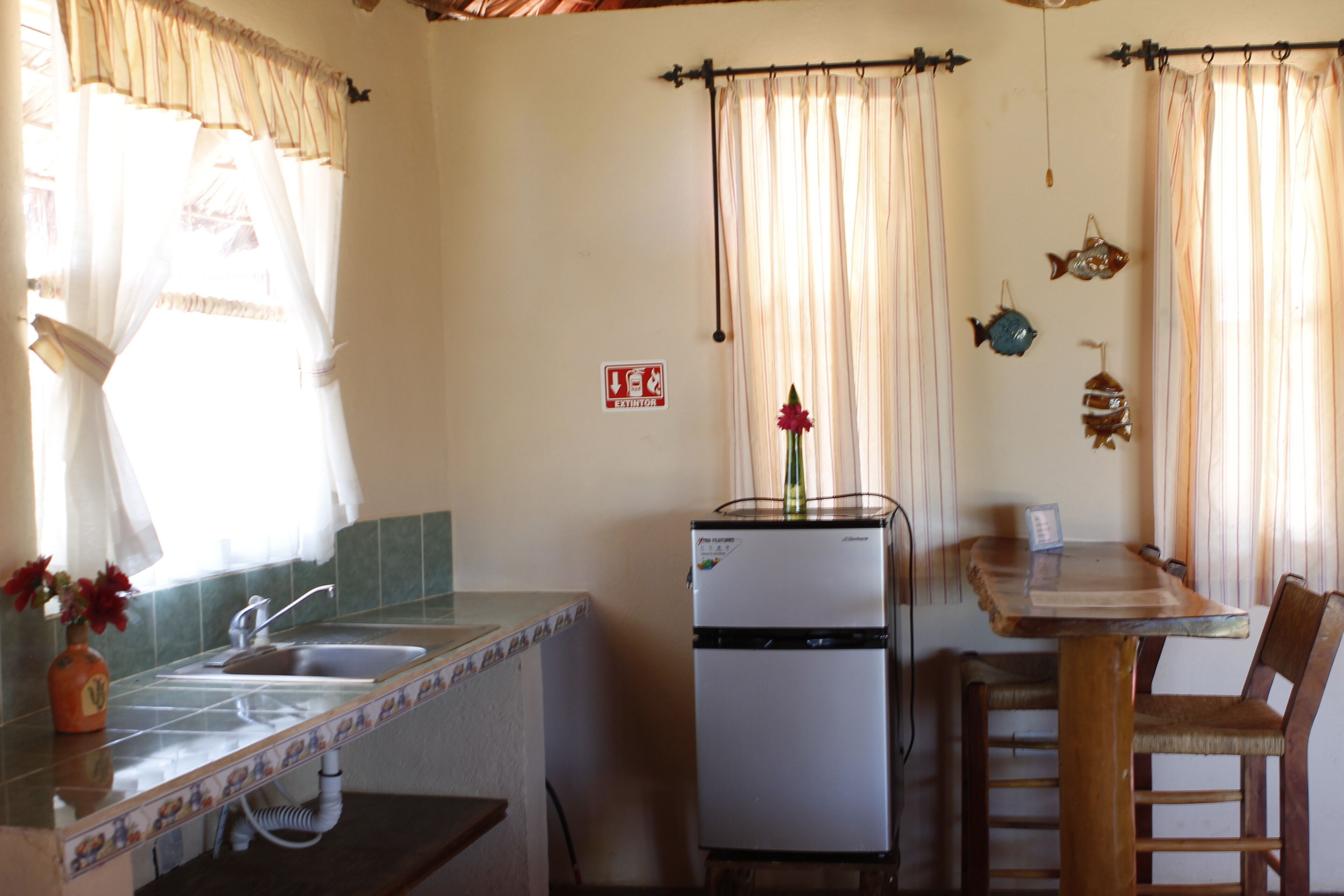 A compact kitchen with a refrigerator, sink, and a dining table with chairs.