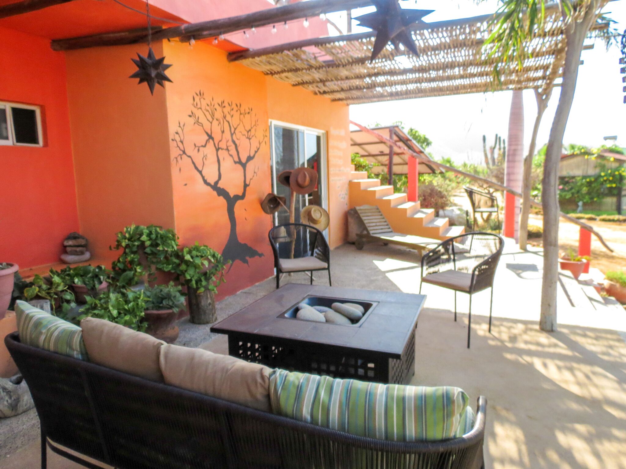 Un patio al aire libre con mobiliario de mimbre, un hogar para fuego y plantas en macetas.
