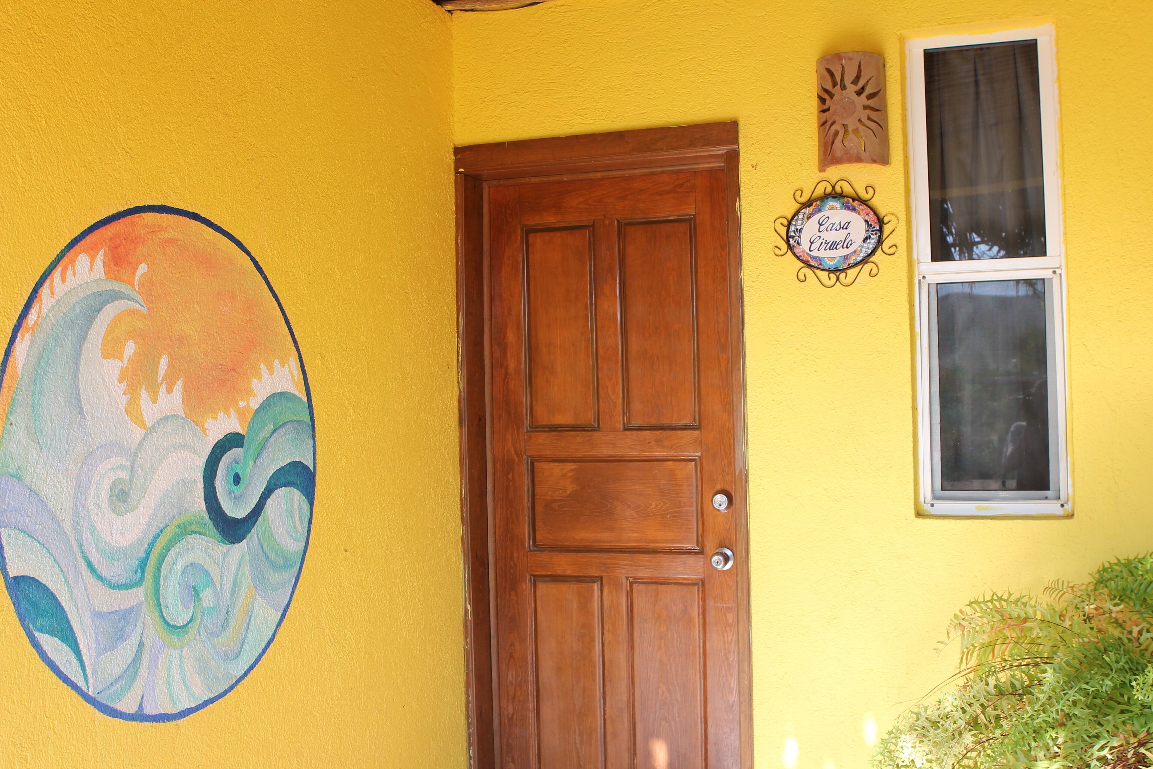 Un mur jaune avec une porte en bois, une fenêtre et un élément décoratif mural.