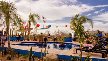 Relax by the pool surrounded by lush cacti and palm trees, with a flagpole nearby.