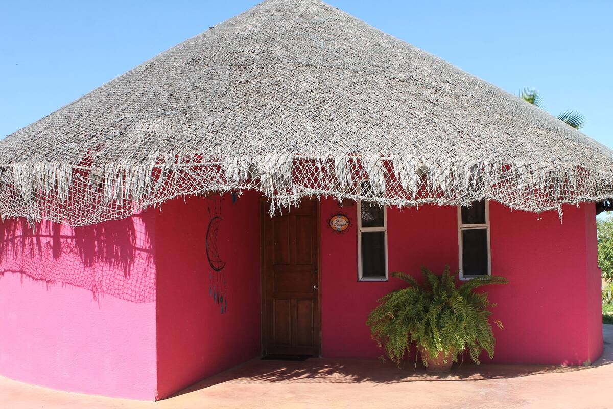Un edificio rojo con techo de paja y puerta de madera.