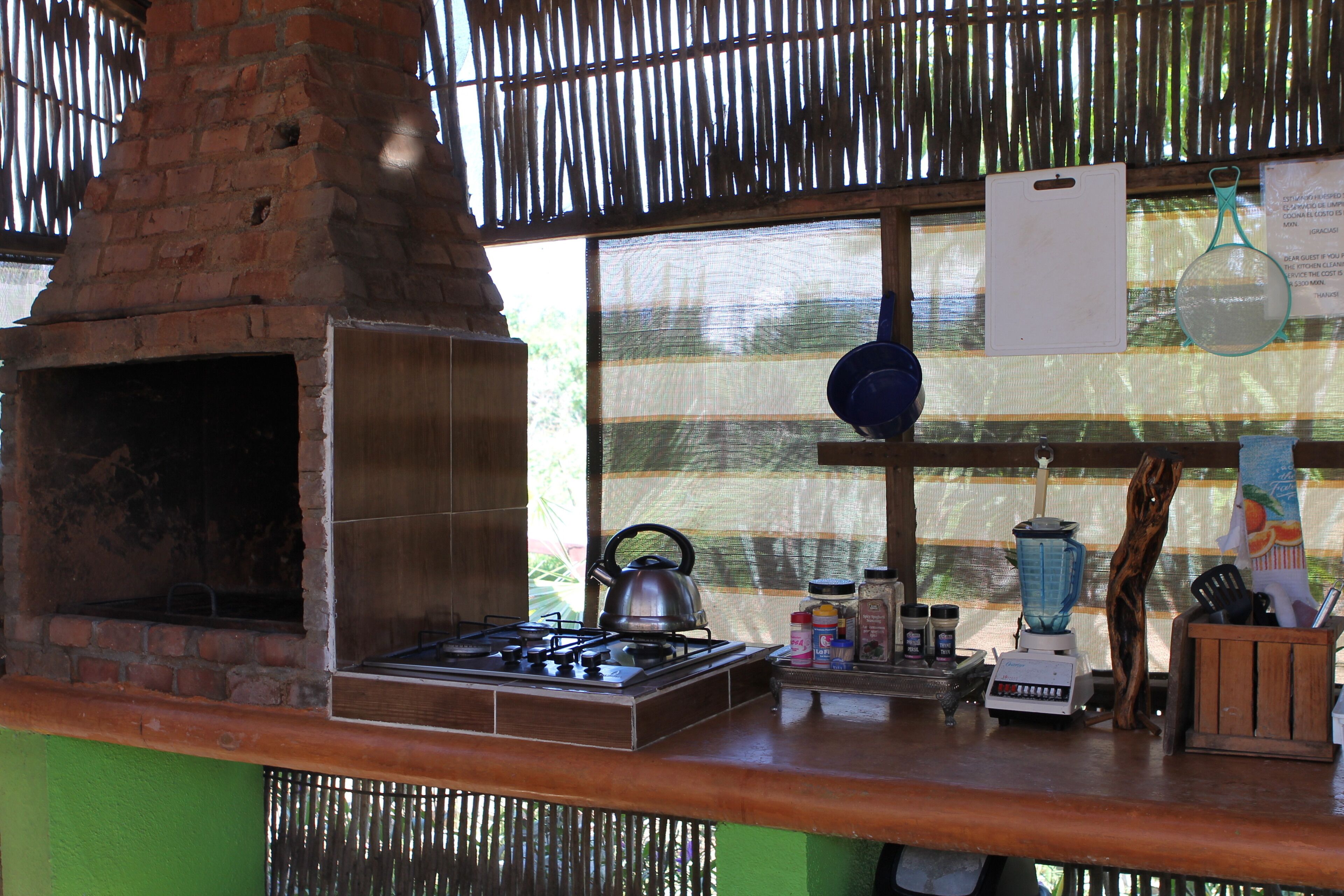 Una cocina con horno de ladrillo, estufa a gas y diversos utensilios.
