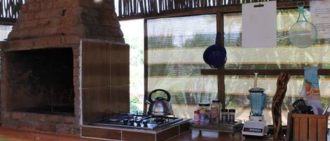Una cocina con horno de ladrillo, estufa a gas y diversos utensilios.
