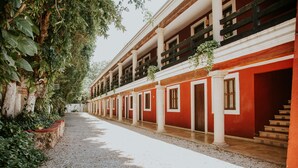 A building with a red facade, white columns, and a gravel pathway.