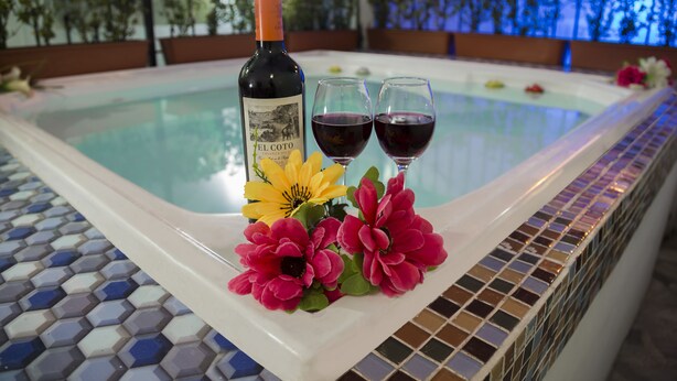 A hot tub with a bottle of wine and glasses, surrounded by flowers. - Hotel Flamingo Cali (Cali)