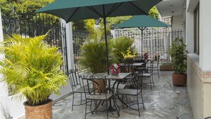 An outdoor patio with stone flooring, metal chairs, tables, and potted plants. - Hotel Flamingo Cali (Cali)