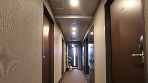 Un couloir d'hôtel avec des revêtements de sol en moquette, des portes en bois et un éclairage encastré.