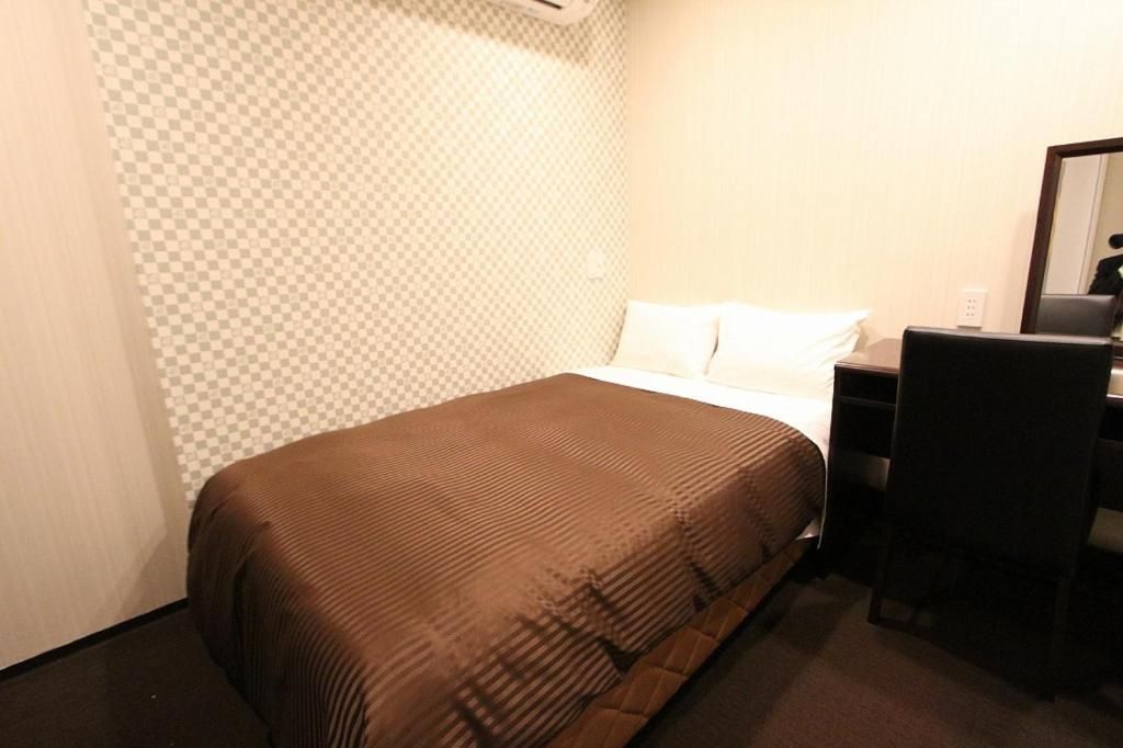A hotel room with a bed, a desk, and a chair.