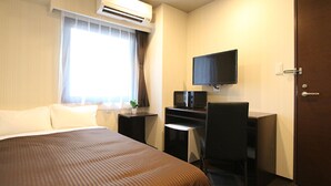 Une chambre d’hôtel équipée d’un lit, d’un bureau avec un ordinateur et une télévision, ainsi que d’un appareil de climatisation.