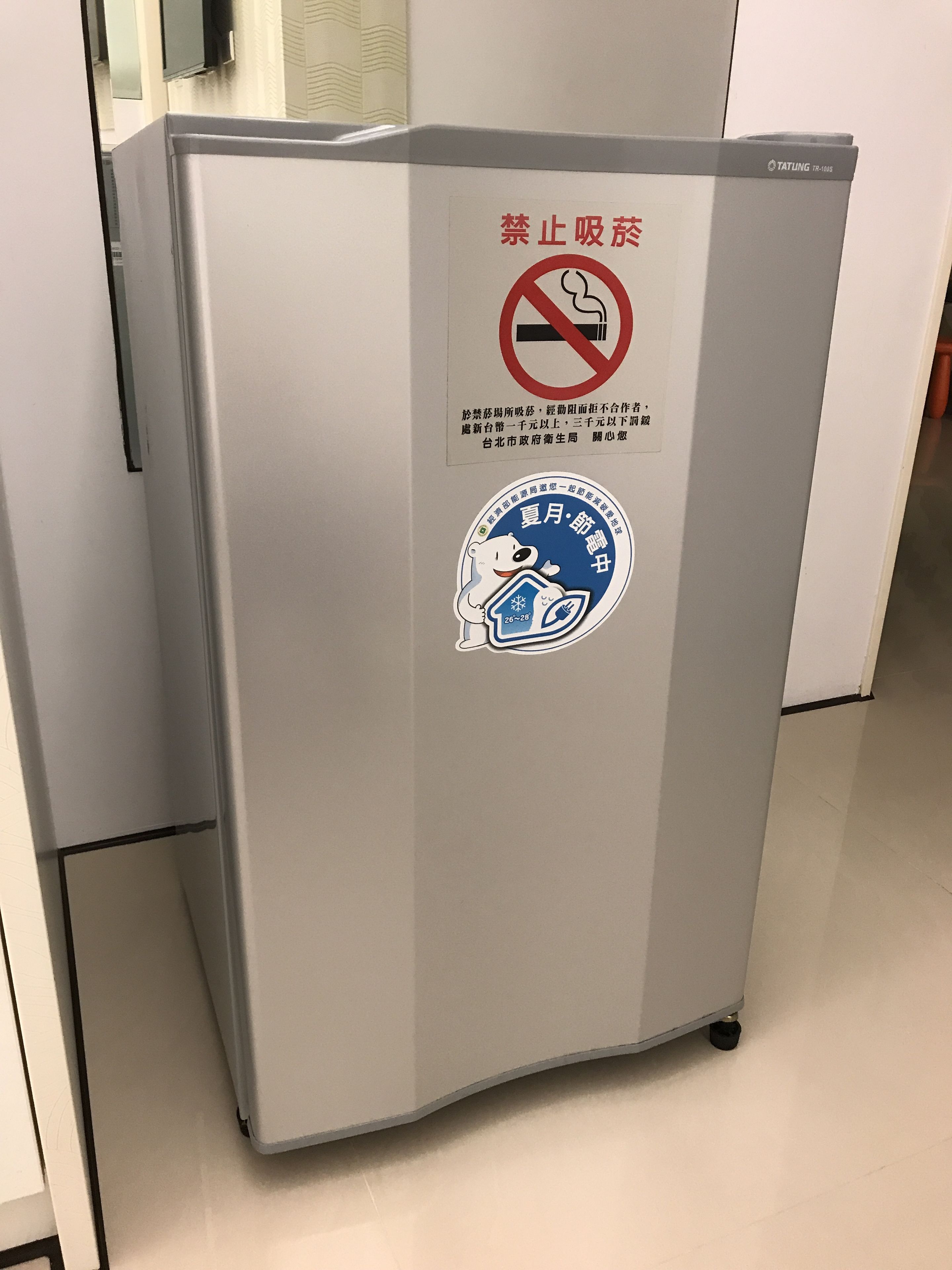 A refrigerator with a sticker prohibiting smoking and a blue sticker with a polar bear.