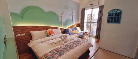 A hotel room with a bed, a small table, and a window with curtains.