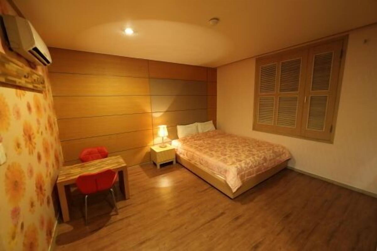 A bedroom with a bed, a desk, and a chair.