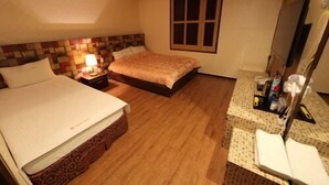 A hotel room with a bed, a nightstand with a lamp, a dresser with toiletries, and a window. - Hotel Ballantine (Cheonan)
