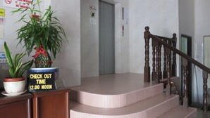 Un hall d’hôtel avec un panneau indiquant l’heure limite pour quitter la chambre, un escalier et un panneau interdisant de fumer.