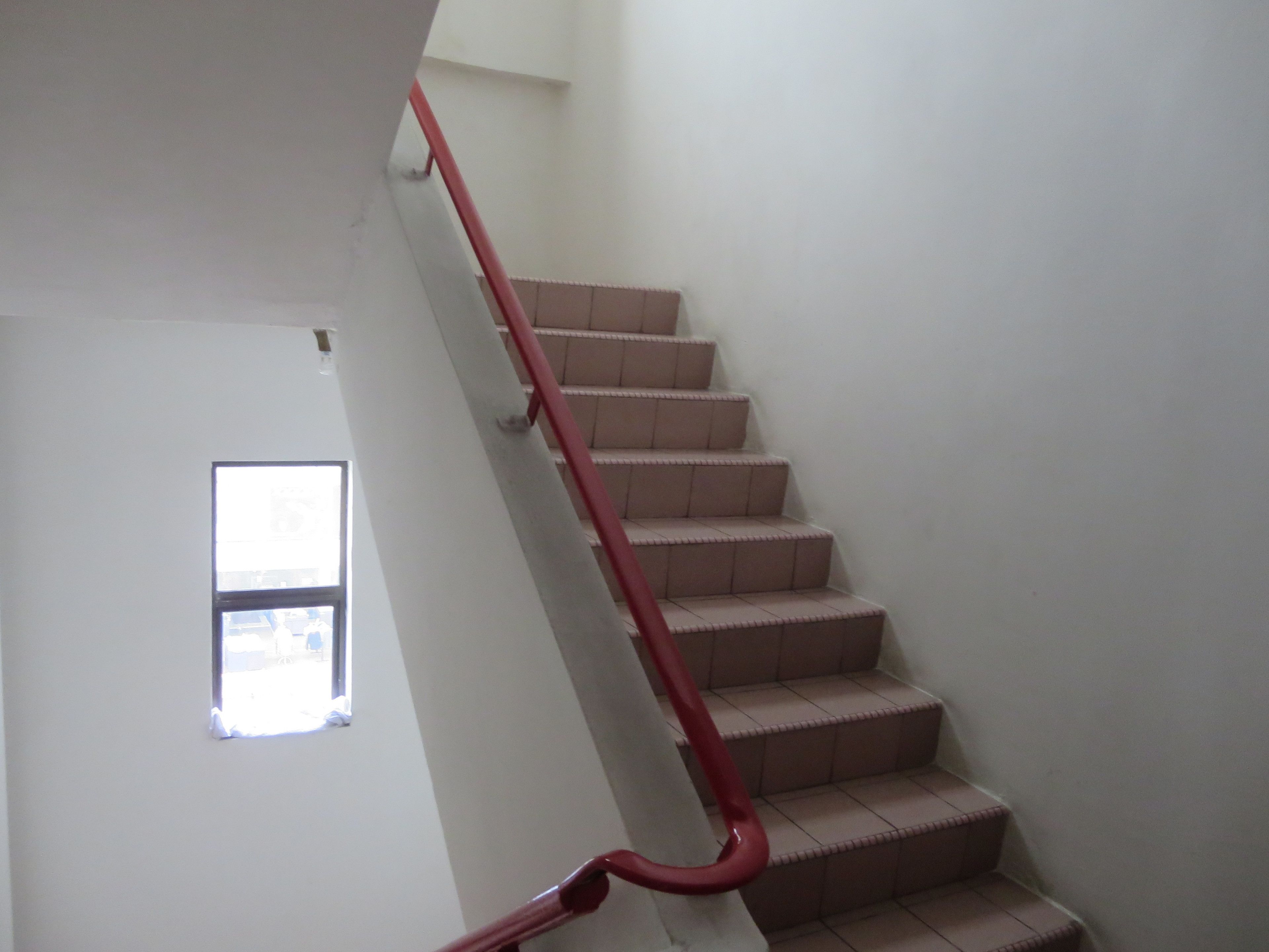 A staircase with a red handrail leading to a landing.