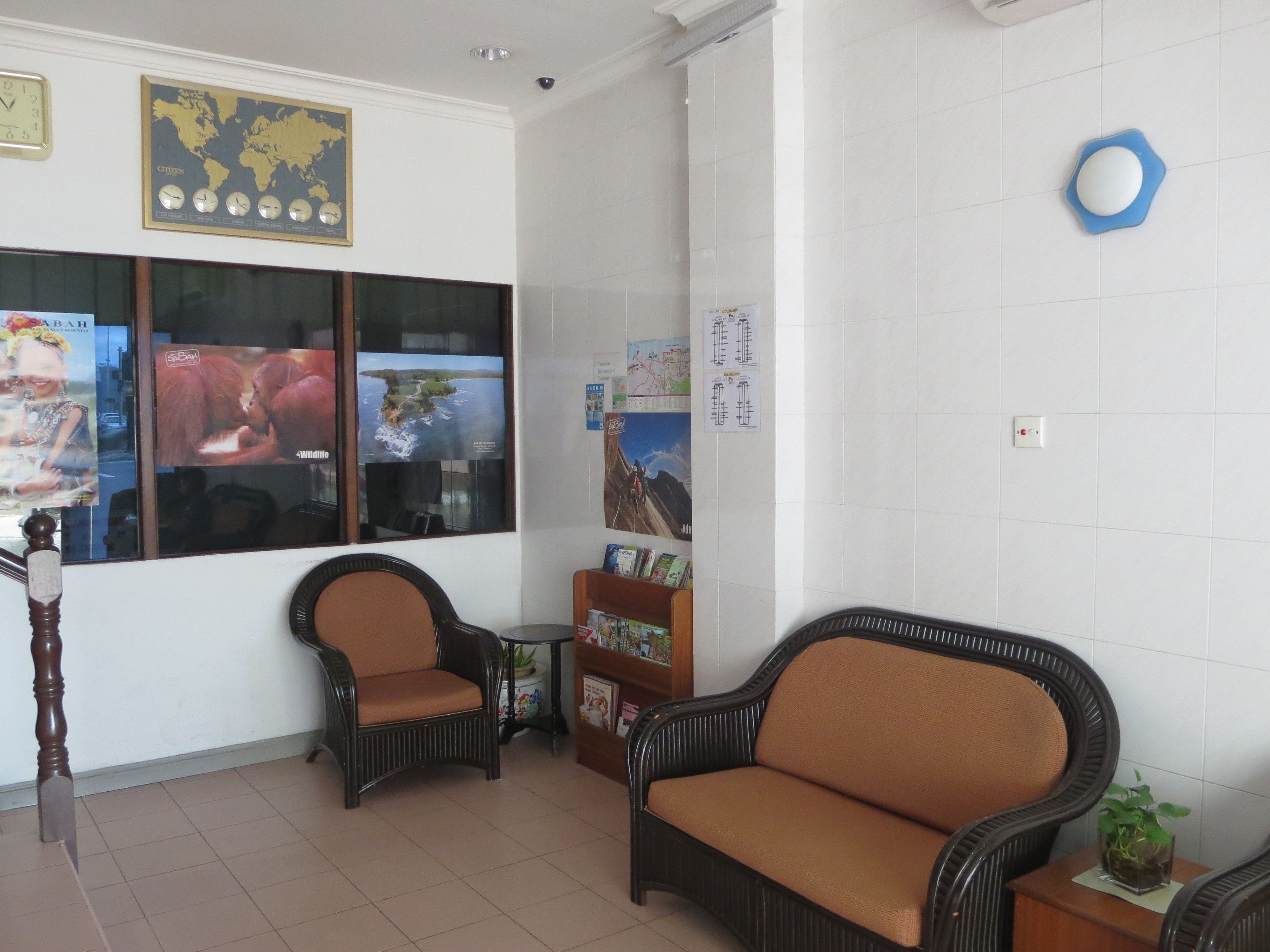 A waiting area with wicker chairs, a wooden staircase, and a world map on the wall.