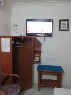 A room with a television mounted on the wall, a wooden desk, a chair, and a wardrobe. - Wah May Hotel (Kota Kinabalu)