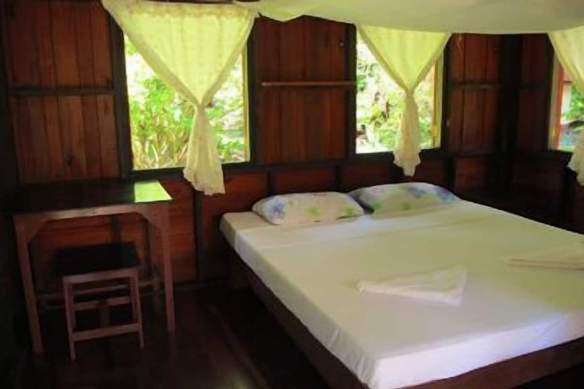 A wooden room with a bed, a desk, and a chair.
