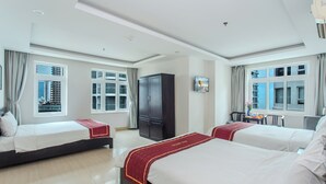 Habitación de hotel con dos camas, un armario, un escritorio con silla y una ventana con cortinas.