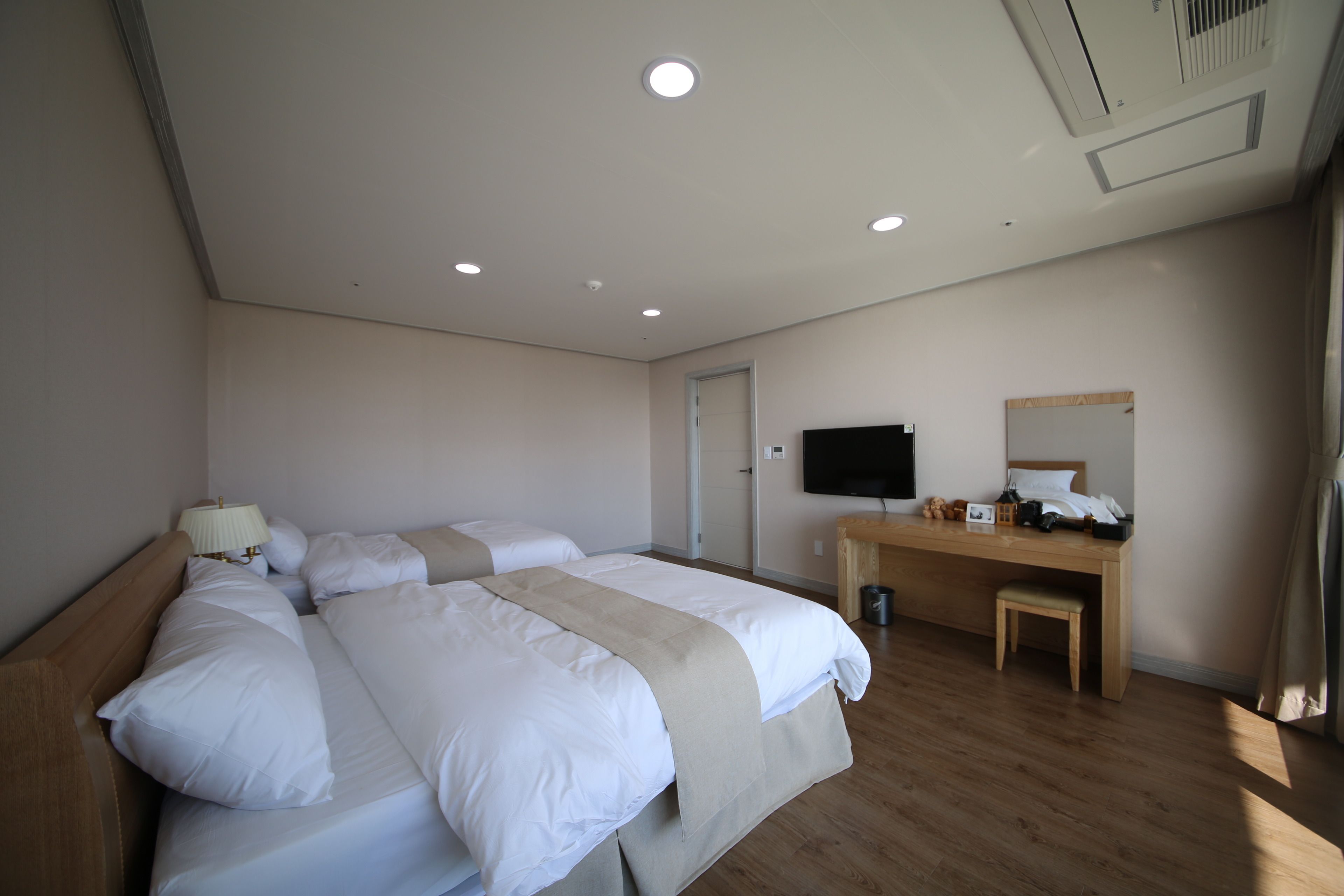 Una camera d'albergo con un letto grande, una scrivania, una televisione e una finestra con tende.
