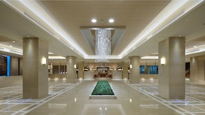 A spacious lobby with a central green plant, large pillars, and a hanging light fixture. - Chihpen Century Hotel (Taimali)