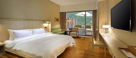 Una habitación de hotel con una cama grande, un escritorio, un televisor de pantalla plana y un balcón con mobiliario exterior.