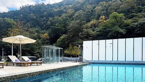 A swimming pool with clear blue water, surrounded by lounge chairs and an umbrella. - Chihpen Century Hotel (Taimali)
