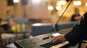 A person playing a keyboard in a room with a microphone stand and a blurred background.